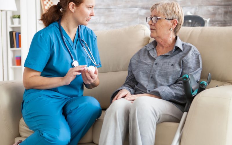 female-nurse-sitting-on-couch-with-senior-woman.jpg
